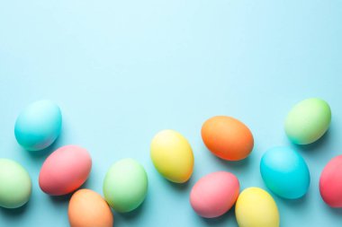 Açık mavi arka planda birçok Paskalya yumurtası boyanmış. Metin için boşluk