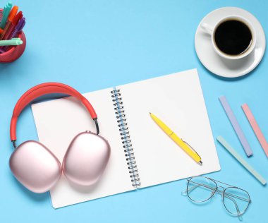 Kulaklıklar, kahve, bardaklar ve açık mavi arka plan kırtasiye malzemesi.
