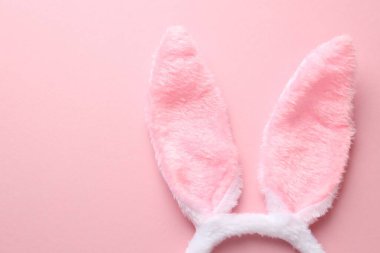 Mutlu Paskalyalar. Pembe arka planda tavşan kulaklı şirin saç bandı, üst manzara. Metin için boşluk