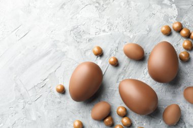 Paskalya kutlaması. Gri desenli masa üzerinde bir sürü çikolata yumurtası ve dragee, metin için boşluk ile düz yatıyordu.