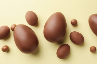 Paskalya kutlaması. Sarı arka planda bir sürü çikolata yumurtası ve dragee, düz yatıyordu.
