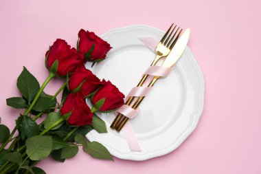 Pembe arka planda güller olan güzel masa ayarları, düz yatış.