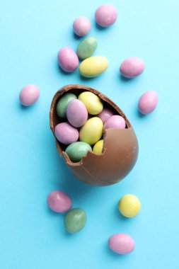 Paskalya kutlaması. Açık mavi arka planda şekerli kırık çikolata yumurtası.
