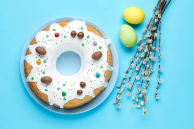 Lezzetli Paskalya pastası, söğüt dalları ve açık mavi arka planda boyanmış yumurtalar, düz uzanmış.