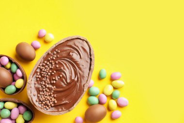 Mutlu Paskalyalar. Sarı arka planda renkli şekerlemeli leziz çikolatalı yumurtalar. Metin için boşluk