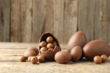 Mutlu Paskalyalar. Ahşap masada şekerli çikolatalı yumurtalar, yakın plan. Metin için boşluk