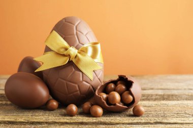 Mutlu Paskalyalar. Ahşap masadaki çikolatalı yumurtalar, renkli arka plana karşı, yakın plan. Metin için boşluk