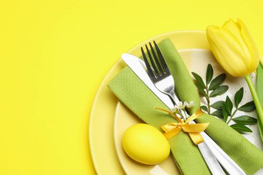 Paskalya kutlaması. Lale çiçeği, yeşil yapraklar ve sarı arka planda boyanmış yumurta, üst manzara. Metin için boşluk