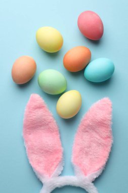 Mutlu Paskalyalar. Şirin tavşan kulakları ve açık mavi arka planda boyanmış yumurtalar.