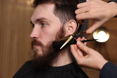 Berber dükkanında adamın sakalını buduyor, yakın plan.