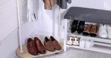 Ayakkabı deposu. Beyaz duvarın yanında farklı ayakkabılar, sağa hareket eden kamera.