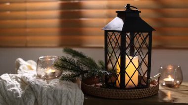 Noel feneri, yanan mumlar, kapalı alandaki bankta bulunan süveter ve köknar dalları, yakın plan. Kamera sola ve geriye hareket ediyor