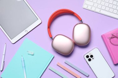 Kulaklıklar, akıllı telefon, tablet, bilgisayar klavyesi ve menekşe arkaplan kırtasiyesi, düz konum