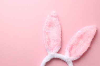Mutlu Paskalyalar. Pembe arka planda tavşan kulaklı şirin saç bandı, üst manzara. Metin için boşluk