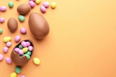 Soluk turuncu arka planda çikolatalı Paskalya yumurtaları ve şekerler. Metin için boşluk