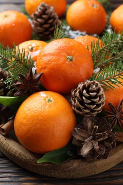 Olgun mandalinalar, baharatlar, kar, köknar ağacı dalları ve kozalaklar ahşap masada, yakın plan.