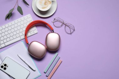 Kulaklıklar, akıllı telefon, bilgisayar klavyesi, mor arka planda kahve ve kırtasiye malzemesi, düz konum. Metin için boşluk