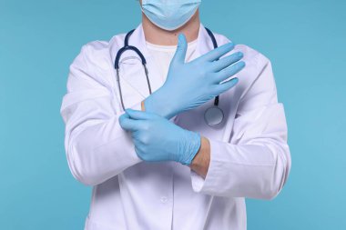 Doktor açık mavi arka plana eldiven takıyor, yakın plan.