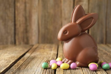 Mutlu Paskalyalar. Ahşap masada renkli şekerli çikolatalı tavşan, yakın plan. Metin için boşluk