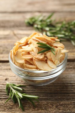 Kasede kurutulmuş sarımsak gevreği ve ahşap masada biberiye, yakın plan.