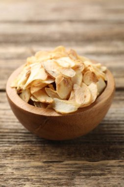 Tahta masadaki kasede kurutulmuş sarımsak taneleri, yakın plan.