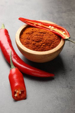 Kırmızı biber ve kırmızı biber tozu gri masada, yakın plan.