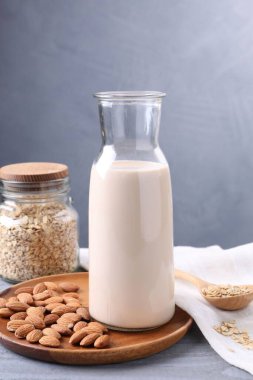 Badem sütü, fındık ve yulaf ezmesi. Gri ahşap masa, yakın plan.
