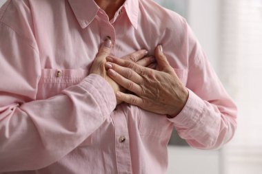 Kalp krizi geçirdi. Üst düzey kadın göğüs ağrısı çekiyor. Kapalı bir yerde, yakın plan.