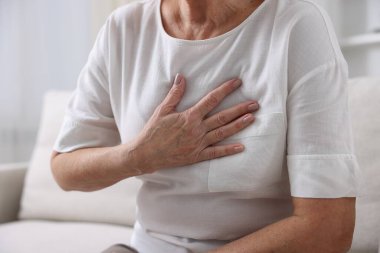 Kalp krizi geçirdi. Üst düzey kadın göğüs ağrısı çekiyor. Kapalı bir yerde, yakın plan.