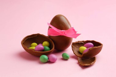 Çikolata yumurtaları ve pembe arka planda renkli şekerler, yakın plan. Mutlu Paskalyalar