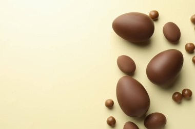Paskalya kutlaması. Sarı arka planda bir sürü çikolata yumurtası ve sürükleyici var, düz bir zeminde metin için yer var.