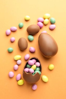 Soluk turuncu arka planda çikolatalı Paskalya yumurtası ve şekeri.