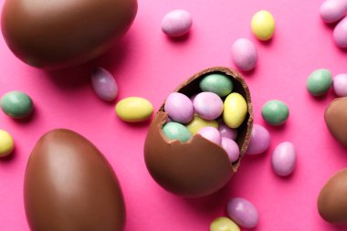 Çikolatalı Paskalya yumurtaları pembe arka planda şekerli, düz yatıyordu.