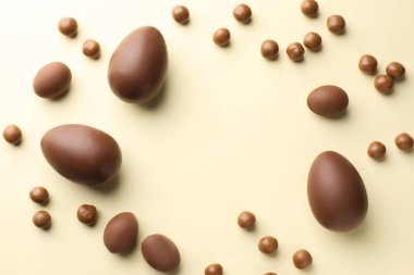 Bej arka planda çikolatalı Paskalya yumurtaları ve şekerler, düz konum. Metin için boşluk