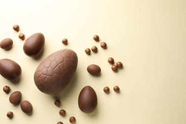 Bej arka planda çikolatalı Paskalya yumurtaları ve şekerler, düz konum. Metin için boşluk