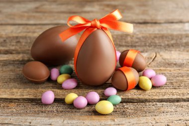 Ahşap masada renkli şekerlemeli lezzetli çikolata yumurtaları, yakın plan. Mutlu Paskalyalar