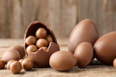 Ahşap masada şekerli çikolatalı yumurtalar, yakın plan. Mutlu Paskalyalar