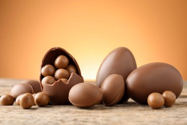 Ahşap masadaki çikolatalı yumurtalar, renkli arka plana karşı, yakın plan. Mutlu Paskalyalar