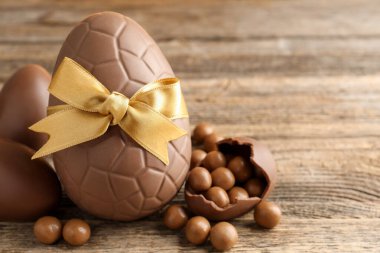 Mutlu Paskalyalar. Ahşap masada şekerli çikolatalı yumurtalar, yakın plan. Metin için boşluk