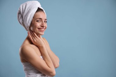 Açık mavi arka planda havluya sarılı güzel bir kadın, mesaj için yer var.