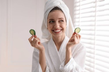 Havluya sarılı güzel bir kadın ve pencerenin yanında salatalık dilimleri.