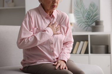 Kalp krizi geçirdi. Üst düzey kadın göğüs ağrısı çekiyor. Kapalı bir yerde, yakın plan.