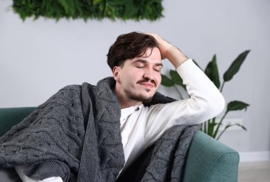 Ekoseli adam evdeki kanepede dinleniyor.