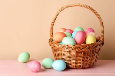 Güzel Paskalya yumurtaları pembe ahşap masada, bej arka planda. Metin için boşluk