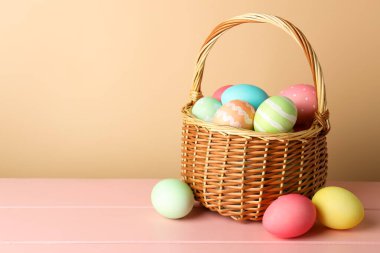 Güzel Paskalya yumurtaları pembe ahşap masada, bej arka planda. Metin için boşluk