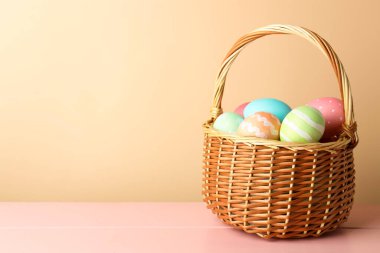 Güzel Paskalya yumurtaları pembe ahşap masada, bej arka planda. Metin için boşluk