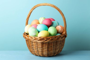 Masadaki sepetteki güzel Paskalya yumurtaları açık mavi arka planda