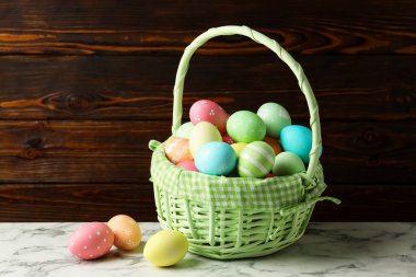 Güzel Paskalya yumurtaları sepetin içinde beyaz mermer masa üzerinde ahşap arka planda