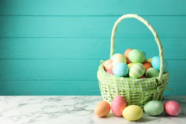 Mavi ahşap arka planda beyaz mermer masada sepetli güzel Paskalya yumurtaları. Metin için boşluk