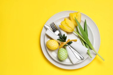 Paskalya kutlaması. Lale çiçekleri ve sarı arka planda boyanmış yumurtalar, üst manzara. Metin için boşluk